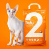 En pose med tofu-kattegrus med en hvid kat bagved