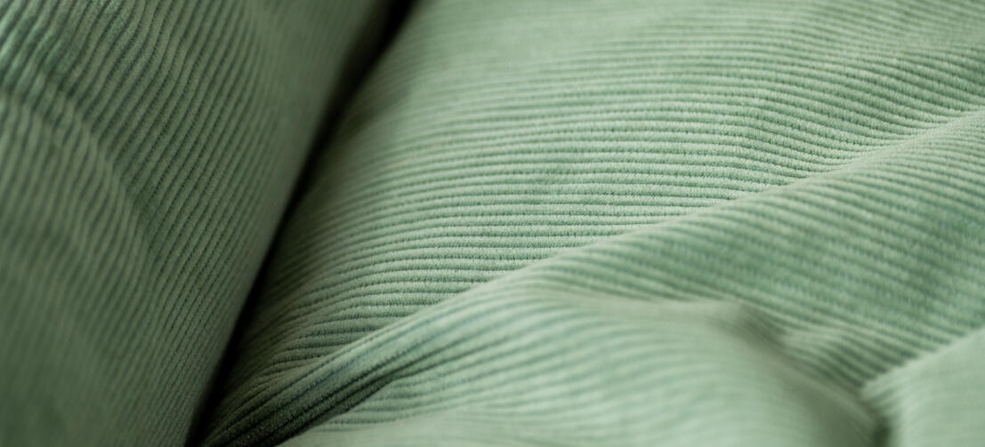 Nærbillede af fløjlstekstur på rede-hundeseng med Corduroy Moss-print.