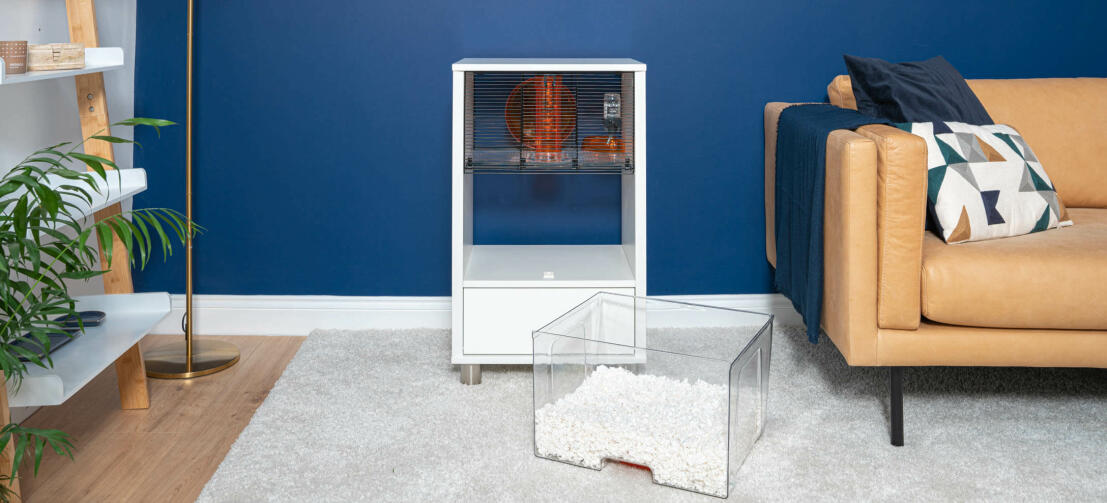 Moderne hvidt Qute hamsterbur med bundbakken taget ud i en stue.