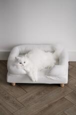 En hvid kat, der nyder komforten i sin hvide seng