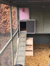 En Autodoor, der er knyttet til en stor hønsegård af træ med en rampe op til døren