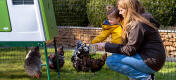 Mor og datter passer høns ved siden af Eglu Cube hønsehus