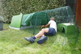 En person, der viser, hvordan man rengør en kaninbane, der er forbundet med en grøn hytte