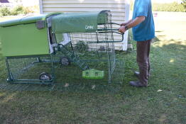 En person, der viser, hvordan man flytter en hønsegård ved hjælp af hjul og håndtag