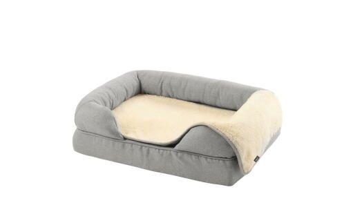 En grå skumgummibolster seng størrelse small 24 med et plys-tæppe ovenpå
