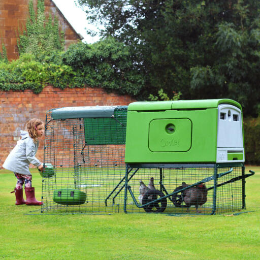 Grønt, stort Eglu Cube hønsehus og hønsegård i haven med pige