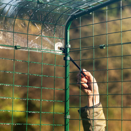 En hånd, der fastgør dækslet til walk in run med bungee-kroge