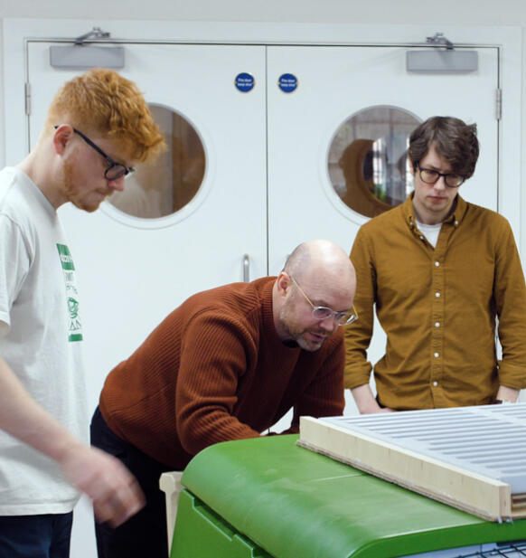 Fire mænd undersøger Eglu Cube hønsegård i et værksted