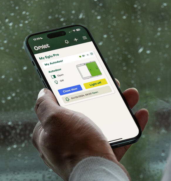 Hånd, der holder en telefon med Omlets smarte Autodoor-app åben