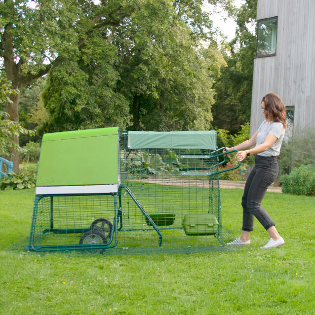 En kvinde flytter et Eglu Go op hønsehus